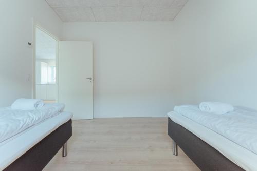 2 łóżka w pokoju z białymi ścianami w obiekcie New 2 BR Apt - Ocean and Mountain View w mieście Torshavn