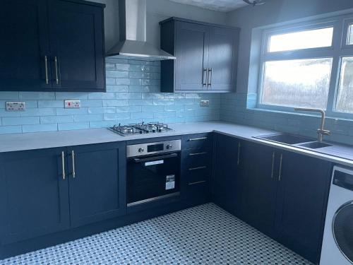 a kitchen with black cabinets and a stove and a window at NEW 3-Bedroom Newcastle House in Lemington