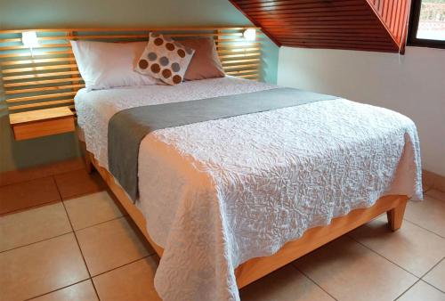 a bedroom with a bed with a white comforter at Trebol Amarillo Bed & Breakfast in Escazu