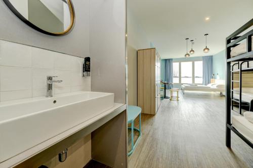 La salle de bains est pourvue d'un lavabo et d'un miroir mural. dans l'établissement MEININGER Venezia Mestre, à Mestre