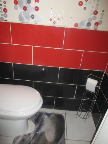 łazienka z toaletą i czerwonymi i czarnymi kafelkami w obiekcie Bellevue w mieście La Tour-dʼAuvergne