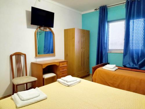 Zimmer mit 2 Betten, einem Schreibtisch und einem Spiegel in der Unterkunft Nefama Pensao in Ourique