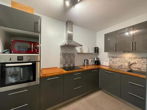 a kitchen with gray cabinets and a microwave at « Esprit cosy », terrasse, piscine, proche Lyon in Tassin-la-Demi-Lune
