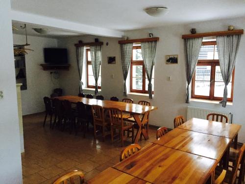 uma sala de jantar com mesas e cadeiras de madeira e janelas em Chata Čert em Josefuv Dul