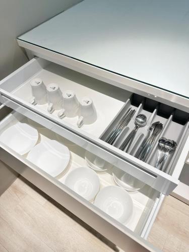 a drawer filled with white plates and utensils at Atria Sofo Suites - Petaling Jaya in Petaling Jaya