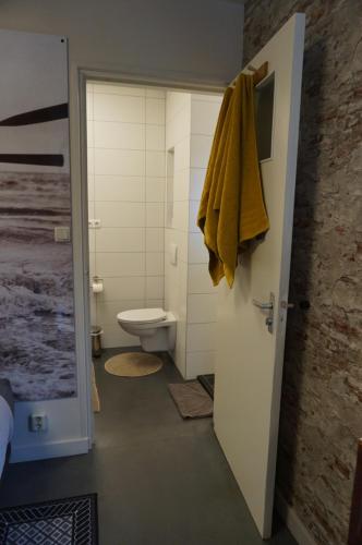 a bathroom with a toilet and a yellow towel on the door at D'rommels Goed Slapen in Den Helder