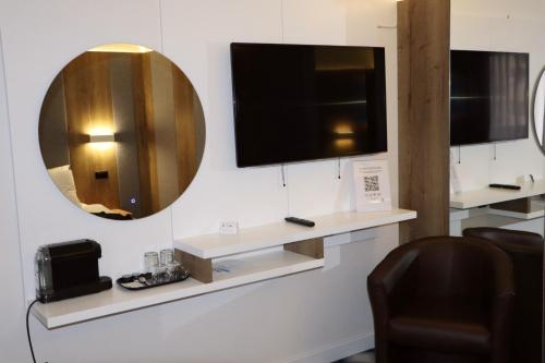 a mirror on a wall with a tv and a chair at Swiss Plus Hotel in Bihać
