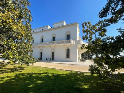 a large white house with trees in the foreground at Sa Suites in Trepuzzi