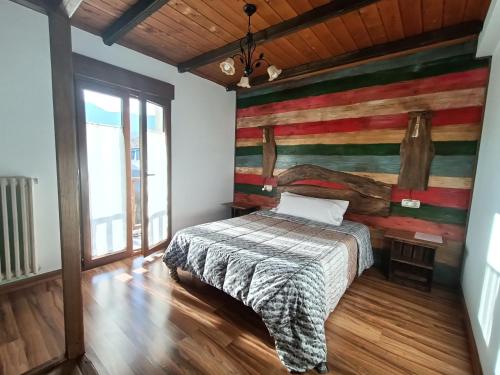1 dormitorio con 1 cama y pared de madera en Cornatel Médulas, en Borrenes