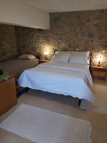 um quarto com uma grande cama branca e uma parede de pedra em Stymfalia stone house 