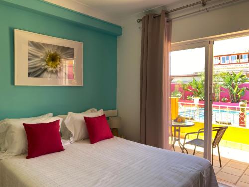 1 dormitorio con 1 cama con almohadas rojas y balcón en Vila Graciosa - Tranquility Oasis, en Lagos