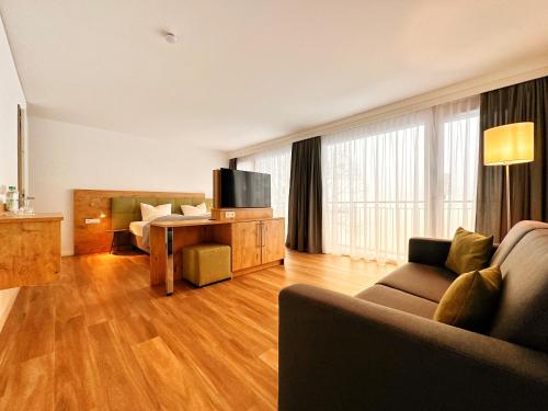 uma sala de estar com um sofá e uma mesa com uma televisão em Seespitz Gästehaus em Herrsching am Ammersee