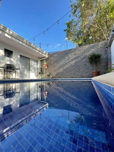 a swimming pool with blue tiles on the side of a house at Casa Encanto Luz del Mar, Con Piscina Privada in Herradura