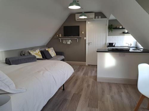 a bedroom with a white bed and a kitchen at Suffolk View Apartment in Tuddenham