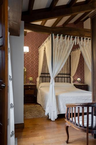 a bedroom with a bed with curtains and a bench at Casa Curiscada in Burres