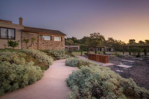 a walkway in front of a house with bushes at Hotel Mas del Sol in Vall-Llobrega