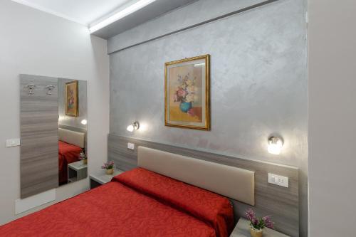 1 dormitorio con cama roja y espejo en Affittacamere Alessia, en San Remo