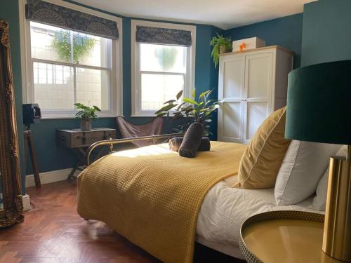 a bedroom with a bed with a yellow blanket and two windows at Cosy Courtyard Apartment in Kemptown in Brighton & Hove