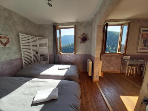 a bedroom with two beds and a desk and two windows at B&B Le Rupicapra in Roubion