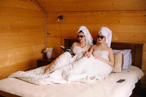 duas mulheres em vestidos de noiva sentadas numa cama em Pearl of Bukovina em Lipovany