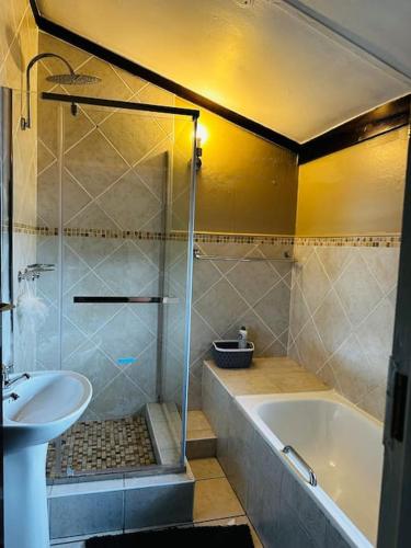 A Cozy Secure 2-Bed Apartment with a lovely garden في غابورون: حمام مع دش وحوض استحمام ومغسلة