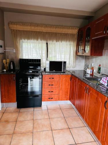 a kitchen with a black stove and a microwave at A Cozy Secure 2-Bed Apartment with a lovely garden in Gaborone