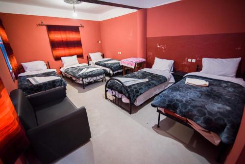 three beds in a room with red walls at Etoile des Gorges in Aït Baha