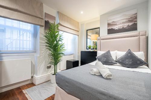 a bedroom with a large bed and a plant at Goodge Apartments in London