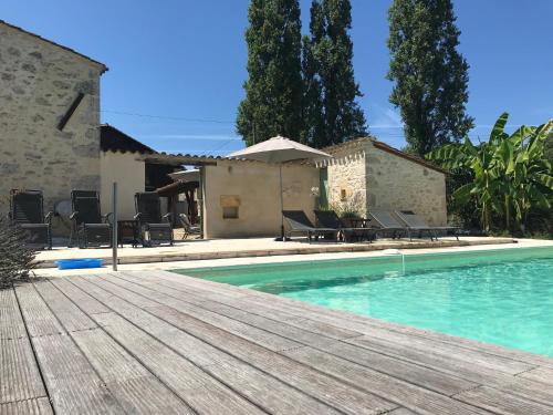 une piscine avec une terrasse en bois à côté d'une maison dans l'établissement La Maison du Lac****, à Saint-Martin-de-Gurçon