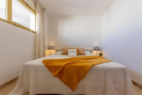 een witte slaapkamer met een bed met een gele deken erop bij Acacias Vista Mar Arysal in Salou