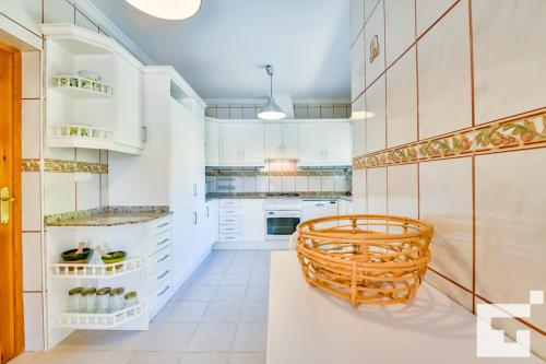 a kitchen with white cabinets and a wicker chair at Villa Angeles - Grupo Turis in Calpe