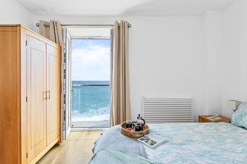 a bedroom with a bed and a view of the ocean at 14 At The Beach, Torcross in Beesands