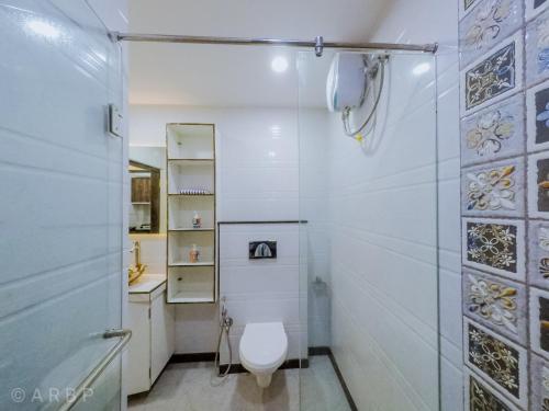 a white bathroom with a toilet and a shower at Moroccan Suite Calangute Beach Vibe in Calangute