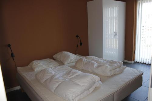 a bed with white sheets on it in a room at Slettestrandvej Apartment - Slettestrandvej 130 nr. 3 - ID 623 in Slettestrand