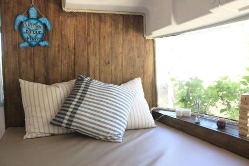1 cama con 2 almohadas en una habitación con ventana en Casa Bus los Guanacastes en Veintisiete de Abril