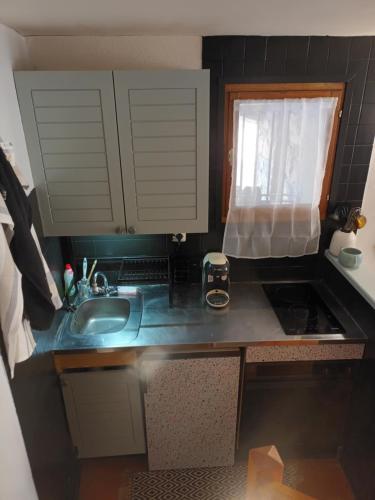 una piccola cucina con lavandino e finestra di Maisonnette au cœur des Angles a Les Angles