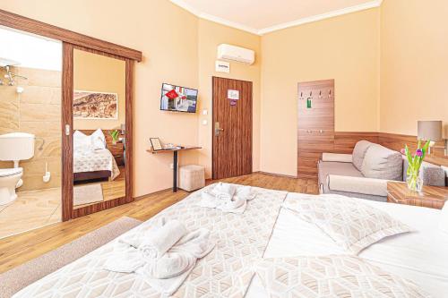 1 dormitorio con 1 cama blanca grande y 1 sofá en Forum Hotel en Szombathely