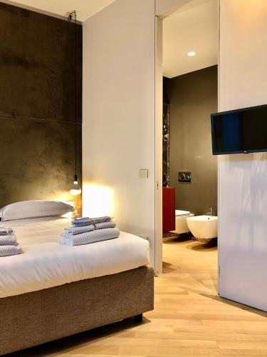 ein Schlafzimmer mit einem Bett und einem TV sowie ein Badezimmer in der Unterkunft Fifty Eight Suite Milan Cerva in Mailand