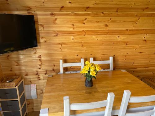 a dining room table with a vase of flowers on it at Fox's Den in Bathgate