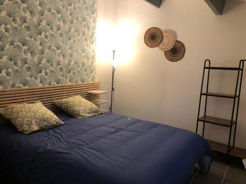 um quarto com uma cama azul e 2 almofadas em gite Au Bout du Chemin em Le Pouget