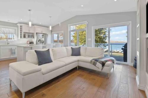 a living room with a white couch and a kitchen at Impressive Modern Waterfront Home on Georgian Bay in Port McNicoll
