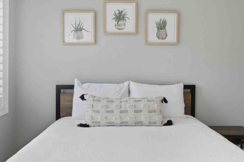 a bedroom with a white bed with three pictures on the wall at Impressive Modern Waterfront Home on Georgian Bay in Port McNicoll