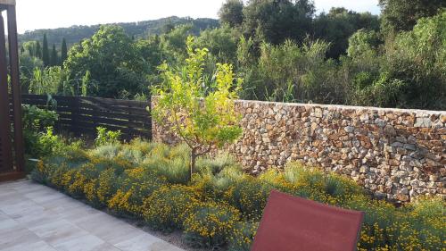a garden with a stone retaining wall and a tree at Hotel Mas del Sol in Vall-Llobrega