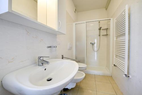 Baño blanco con lavabo y aseo en Malcesine Dream Apartments, en Malcesine