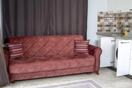 a red couch with two pillows on it in a kitchen at ADRASAN HİMERA APART & BUNGALOW in Adrasan