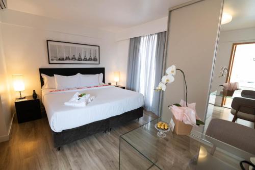a bedroom with a large white bed and a living room at H2 Platinum Lourdes in Belo Horizonte