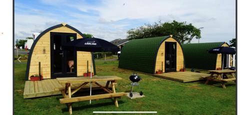 a group of tents with tables and an umbrella at Gateway Glamping Pods in Llanelli