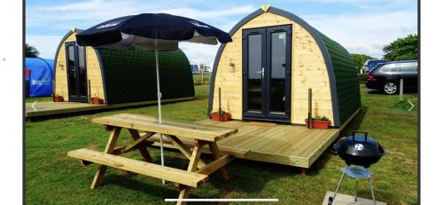 a tiny house with a picnic table and an umbrella at Gateway Glamping Pods in Llanelli