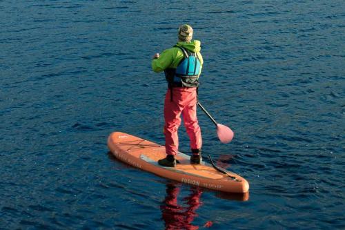 a man standing on a paddle board in the water at Loch Rannoch Hotel and Spa in Kinloch Rannoch