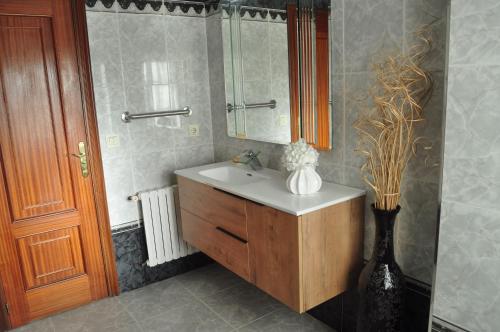 a bathroom with a sink and a vase of flowers at Casa Barranqueiro in Vilaboa